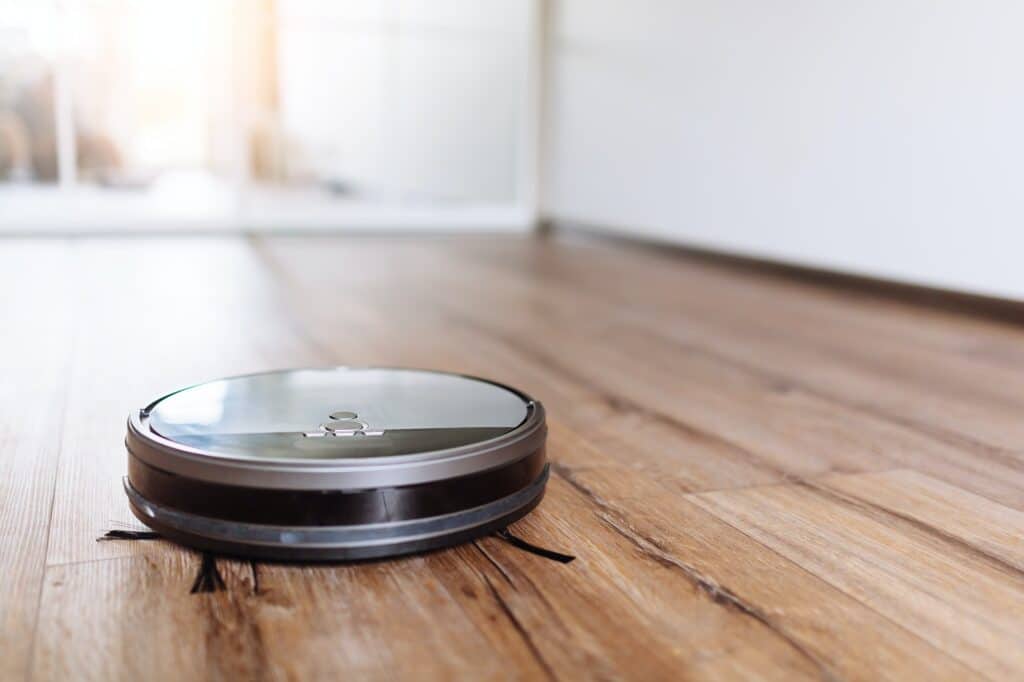 Robotic vacuum cleaner on laminate wood floor smart cleaning technology. Selective focus
